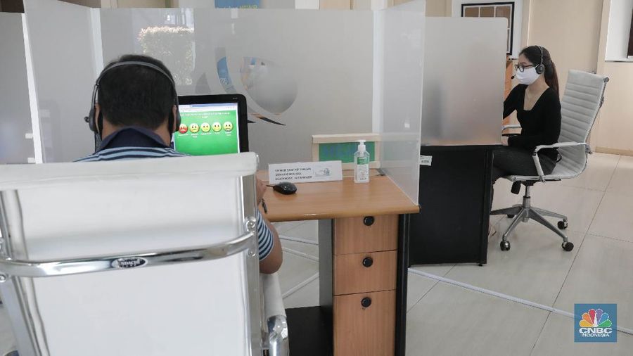 Peserta BP Jamsostek konsultasi layanan tanpa kontak fisik dengan virtual di Kantor Cabang BPJS Ketenagakerjaan Cilandak, Kamis (18/6/2020). Layanan secara virtual ini merupakan penerapan sesuai dengan protokol kesehatan tanpa harus kontak langsung antara petugas dan peserta BP Jamsostek dalam rangka mencegah penularan COVID-19. Kepala Kantor Cabang Puspitaningsih mengatakan adanya layanan konsultasi tanpa kontak fisik ini di Cabang Cilandak ini disesuaikan dengan aturan protokol kesehatan dan untuk memutus penyebaran Covid-19.  Kantor cabang ini menyediakan skat-skat yang dilengkapi layar monitor yang terhubung dengan petugas secara video conference untuk kebutuhan komunikasi dan verifikasi data. 