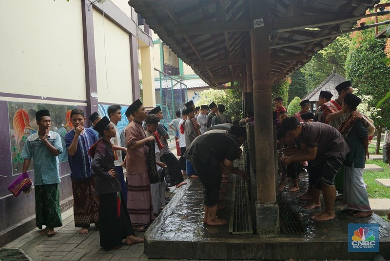 Suasana Pesantren An-Nuqthah, Tangerang Banten, sejumlah santri kembali berdatangan usai belajar di rumah selama pandemi corona. 18/6/20. CNBC Indonesia/Tri Susilo Para santri juga harus mengenakan masker walaupun sudah berada di dalam pesantren. Pemulangan santri ke pesantren dilakukan selama beberapa tahap dalam satu minggu. Ini dilakukan guna menghindari penumpukan orang dalam satu waktu. Pada tahap awal, santri yang kembali baru sekira 15 persen dari total 1.500 santri. Sementara, sebagian orangtua masih khawatir akan penularan virus corona di dalam pesantren. Karena itu mereka membekali buah hatinya dengan cairan pembersih tangan, vitamin dan persediaan masker. Sementara pengelola pesantren menyebut, kebijakan membuka kembali aktifitas belajar tatap muka karena pihaknya merasa sudah sanggup menerapkan protokol kesehatan di dalam pesantren. Guna penerapan protokol kesehatan, pihak pengelola melakukan sterilisasi lingkungan pesantren secara rutin, menata ulang kamar-kamar tidur para santri, dan menjaga jarak antar individu, baik dalam setiap kegiatan belajar mengajar maupun ibadah. Pantauan CNBC Indonesia Dilapangan para santri yang melakukan ibadah harus tetap jaga jarak didalam masjid. Santri yang balik ke pesantren belum semuanya berdatangan, kemungkinan gelombang kedua akan datang pada bulan Juli 2020 mendatang. (CNBC Indonesia/ Tri Susilo)
