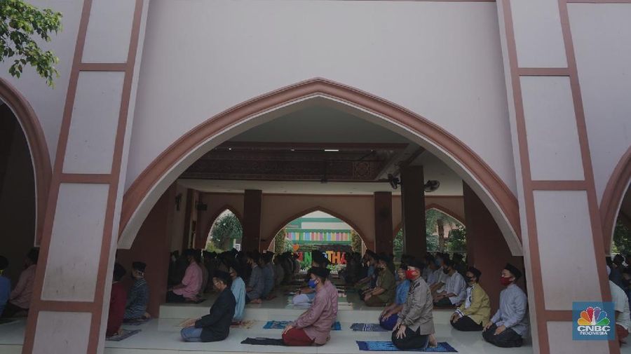 Suasana Pesantren An-Nuqthah, Tangerang Banten, sejumlah santri kembali berdatangan usai belajar di rumah selama pandemi corona. 18/6/20. CNBC Indonesia/Tri Susilo Para santri juga harus mengenakan masker walaupun sudah berada di dalam pesantren. Pemulangan santri ke pesantren dilakukan selama beberapa tahap dalam satu minggu. Ini dilakukan guna menghindari penumpukan orang dalam satu waktu. Pada tahap awal, santri yang kembali baru sekira 15 persen dari total 1.500 santri. Sementara, sebagian orangtua masih khawatir akan penularan virus corona di dalam pesantren. Karena itu mereka membekali buah hatinya dengan cairan pembersih tangan, vitamin dan persediaan masker. Sementara pengelola pesantren menyebut, kebijakan membuka kembali aktifitas belajar tatap muka karena pihaknya merasa sudah sanggup menerapkan protokol kesehatan di dalam pesantren. Guna penerapan protokol kesehatan, pihak pengelola melakukan sterilisasi lingkungan pesantren secara rutin, menata ulang kamar-kamar tidur para santri, dan menjaga jarak antar individu, baik dalam setiap kegiatan belajar mengajar maupun ibadah. Pantauan CNBC Indonesia Dilapangan para santri yang melakukan ibadah harus tetap jaga jarak didalam masjid. Santri yang balik ke pesantren belum semuanya berdatangan, kemungkinan gelombang kedua akan datang pada bulan Juli 2020 mendatang. (CNBC Indonesia/ Tri Susilo)