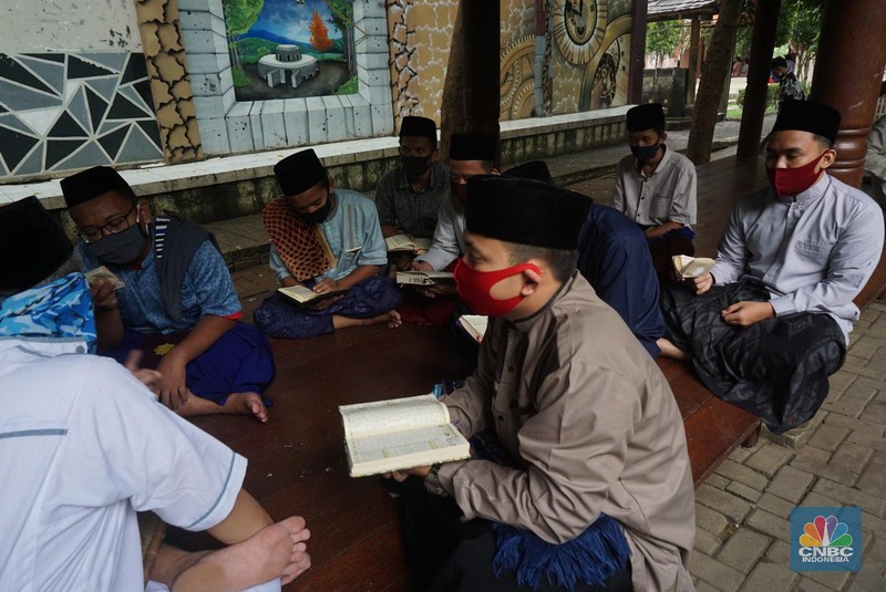 Suasana Pesantren An-Nuqthah, Tangerang Banten, sejumlah santri kembali berdatangan usai belajar di rumah selama pandemi corona. 18/6/20. CNBC Indonesia/Tri Susilo Para santri juga harus mengenakan masker walaupun sudah berada di dalam pesantren. Pemulangan santri ke pesantren dilakukan selama beberapa tahap dalam satu minggu. Ini dilakukan guna menghindari penumpukan orang dalam satu waktu. Pada tahap awal, santri yang kembali baru sekira 15 persen dari total 1.500 santri. Sementara, sebagian orangtua masih khawatir akan penularan virus corona di dalam pesantren. Karena itu mereka membekali buah hatinya dengan cairan pembersih tangan, vitamin dan persediaan masker. Sementara pengelola pesantren menyebut, kebijakan membuka kembali aktifitas belajar tatap muka karena pihaknya merasa sudah sanggup menerapkan protokol kesehatan di dalam pesantren. Guna penerapan protokol kesehatan, pihak pengelola melakukan sterilisasi lingkungan pesantren secara rutin, menata ulang kamar-kamar tidur para santri, dan menjaga jarak antar individu, baik dalam setiap kegiatan belajar mengajar maupun ibadah. Pantauan CNBC Indonesia Dilapangan para santri yang melakukan ibadah harus tetap jaga jarak didalam masjid. Santri yang balik ke pesantren belum semuanya berdatangan, kemungkinan gelombang kedua akan datang pada bulan Juli 2020 mendatang. (CNBC Indonesia/ Tri Susilo)