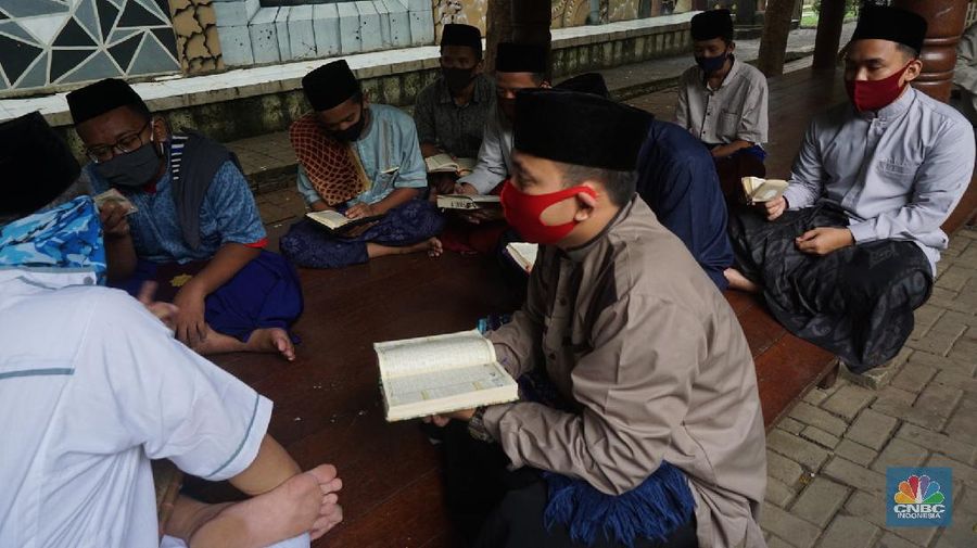 Suasana Pesantren An-Nuqthah, Tangerang Banten, sejumlah santri kembali berdatangan usai belajar di rumah selama pandemi corona. 18/6/20. CNBC Indonesia/Tri Susilo Para santri juga harus mengenakan masker walaupun sudah berada di dalam pesantren. Pemulangan santri ke pesantren dilakukan selama beberapa tahap dalam satu minggu. Ini dilakukan guna menghindari penumpukan orang dalam satu waktu. Pada tahap awal, santri yang kembali baru sekira 15 persen dari total 1.500 santri. Sementara, sebagian orangtua masih khawatir akan penularan virus corona di dalam pesantren. Karena itu mereka membekali buah hatinya dengan cairan pembersih tangan, vitamin dan persediaan masker. Sementara pengelola pesantren menyebut, kebijakan membuka kembali aktifitas belajar tatap muka karena pihaknya merasa sudah sanggup menerapkan protokol kesehatan di dalam pesantren. Guna penerapan protokol kesehatan, pihak pengelola melakukan sterilisasi lingkungan pesantren secara rutin, menata ulang kamar-kamar tidur para santri, dan menjaga jarak antar individu, baik dalam setiap kegiatan belajar mengajar maupun ibadah. Pantauan CNBC Indonesia Dilapangan para santri yang melakukan ibadah harus tetap jaga jarak didalam masjid. Santri yang balik ke pesantren belum semuanya berdatangan, kemungkinan gelombang kedua akan datang pada bulan Juli 2020 mendatang. (CNBC Indonesia/ Tri Susilo)