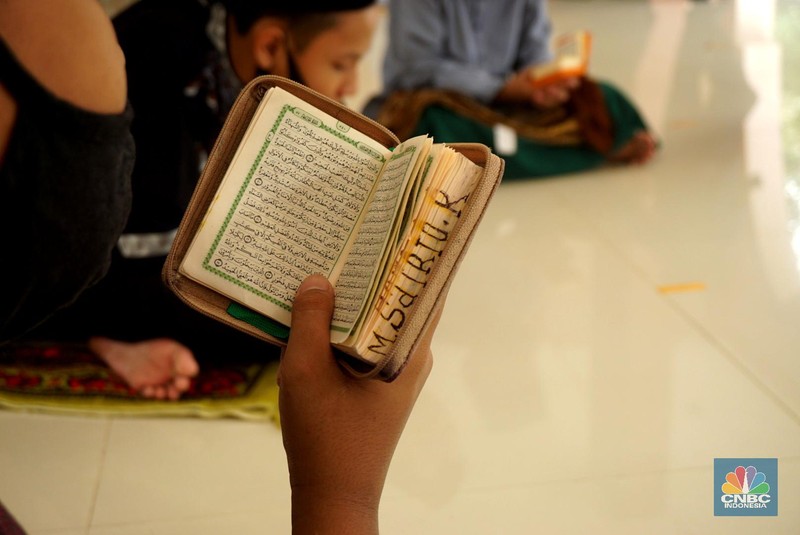 Suasana Pesantren An-Nuqthah, Tangerang Banten, sejumlah santri kembali berdatangan usai belajar di rumah selama pandemi corona. 18/6/20. CNBC Indonesia/Tri Susilo Para santri juga harus mengenakan masker walaupun sudah berada di dalam pesantren. Pemulangan santri ke pesantren dilakukan selama beberapa tahap dalam satu minggu. Ini dilakukan guna menghindari penumpukan orang dalam satu waktu. Pada tahap awal, santri yang kembali baru sekira 15 persen dari total 1.500 santri. Sementara, sebagian orangtua masih khawatir akan penularan virus corona di dalam pesantren. Karena itu mereka membekali buah hatinya dengan cairan pembersih tangan, vitamin dan persediaan masker. Sementara pengelola pesantren menyebut, kebijakan membuka kembali aktifitas belajar tatap muka karena pihaknya merasa sudah sanggup menerapkan protokol kesehatan di dalam pesantren. Guna penerapan protokol kesehatan, pihak pengelola melakukan sterilisasi lingkungan pesantren secara rutin, menata ulang kamar-kamar tidur para santri, dan menjaga jarak antar individu, baik dalam setiap kegiatan belajar mengajar maupun ibadah. Pantauan CNBC Indonesia Dilapangan para santri yang melakukan ibadah harus tetap jaga jarak didalam masjid. Santri yang balik ke pesantren belum semuanya berdatangan, kemungkinan gelombang kedua akan datang pada bulan Juli 2020 mendatang. (CNBC Indonesia/ Tri Susilo)
