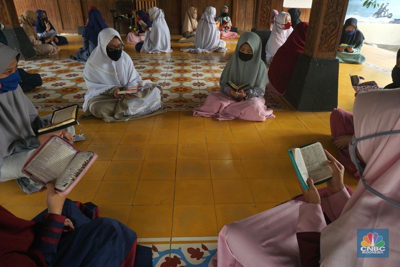 Suasana Pesantren An-Nuqthah, Tangerang Banten, sejumlah santri kembali berdatangan usai belajar di rumah selama pandemi corona. 18/6/20. CNBC Indonesia/Tri Susilo Para santri juga harus mengenakan masker walaupun sudah berada di dalam pesantren. Pemulangan santri ke pesantren dilakukan selama beberapa tahap dalam satu minggu. Ini dilakukan guna menghindari penumpukan orang dalam satu waktu. Pada tahap awal, santri yang kembali baru sekira 15 persen dari total 1.500 santri. Sementara, sebagian orangtua masih khawatir akan penularan virus corona di dalam pesantren. Karena itu mereka membekali buah hatinya dengan cairan pembersih tangan, vitamin dan persediaan masker. Sementara pengelola pesantren menyebut, kebijakan membuka kembali aktifitas belajar tatap muka karena pihaknya merasa sudah sanggup menerapkan protokol kesehatan di dalam pesantren. Guna penerapan protokol kesehatan, pihak pengelola melakukan sterilisasi lingkungan pesantren secara rutin, menata ulang kamar-kamar tidur para santri, dan menjaga jarak antar individu, baik dalam setiap kegiatan belajar mengajar maupun ibadah. Pantauan CNBC Indonesia Dilapangan para santri yang melakukan ibadah harus tetap jaga jarak didalam masjid. Santri yang balik ke pesantren belum semuanya berdatangan, kemungkinan gelombang kedua akan datang pada bulan Juli 2020 mendatang. (CNBC Indonesia/ Tri Susilo)