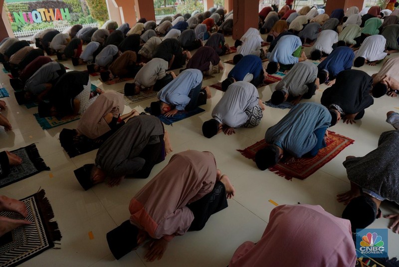 Suasana Pesantren An-Nuqthah, Tangerang Banten, sejumlah santri kembali berdatangan usai belajar di rumah selama pandemi corona. 18/6/20. CNBC Indonesia/Tri Susilo Para santri juga harus mengenakan masker walaupun sudah berada di dalam pesantren. Pemulangan santri ke pesantren dilakukan selama beberapa tahap dalam satu minggu. Ini dilakukan guna menghindari penumpukan orang dalam satu waktu. Pada tahap awal, santri yang kembali baru sekira 15 persen dari total 1.500 santri. Sementara, sebagian orangtua masih khawatir akan penularan virus corona di dalam pesantren. Karena itu mereka membekali buah hatinya dengan cairan pembersih tangan, vitamin dan persediaan masker. Sementara pengelola pesantren menyebut, kebijakan membuka kembali aktifitas belajar tatap muka karena pihaknya merasa sudah sanggup menerapkan protokol kesehatan di dalam pesantren. Guna penerapan protokol kesehatan, pihak pengelola melakukan sterilisasi lingkungan pesantren secara rutin, menata ulang kamar-kamar tidur para santri, dan menjaga jarak antar individu, baik dalam setiap kegiatan belajar mengajar maupun ibadah. Pantauan CNBC Indonesia Dilapangan para santri yang melakukan ibadah harus tetap jaga jarak didalam masjid. Santri yang balik ke pesantren belum semuanya berdatangan, kemungkinan gelombang kedua akan datang pada bulan Juli 2020 mendatang. (CNBC Indonesia/ Tri Susilo)