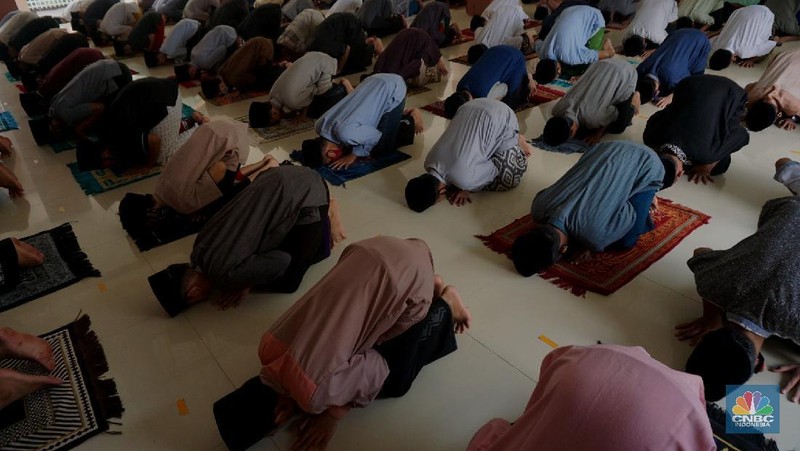 Suasana Pesantren An-Nuqthah, Tangerang Banten, sejumlah santri kembali berdatangan usai belajar di rumah selama pandemi corona. 18/6/20. CNBC Indonesia/Tri Susilo Para santri juga harus mengenakan masker walaupun sudah berada di dalam pesantren. Pemulangan santri ke pesantren dilakukan selama beberapa tahap dalam satu minggu. Ini dilakukan guna menghindari penumpukan orang dalam satu waktu. Pada tahap awal, santri yang kembali baru sekira 15 persen dari total 1.500 santri. Sementara, sebagian orangtua masih khawatir akan penularan virus corona di dalam pesantren. Karena itu mereka membekali buah hatinya dengan cairan pembersih tangan, vitamin dan persediaan masker. Sementara pengelola pesantren menyebut, kebijakan membuka kembali aktifitas belajar tatap muka karena pihaknya merasa sudah sanggup menerapkan protokol kesehatan di dalam pesantren. Guna penerapan protokol kesehatan, pihak pengelola melakukan sterilisasi lingkungan pesantren secara rutin, menata ulang kamar-kamar tidur para santri, dan menjaga jarak antar individu, baik dalam setiap kegiatan belajar mengajar maupun ibadah. Pantauan CNBC Indonesia Dilapangan para santri yang melakukan ibadah harus tetap jaga jarak didalam masjid. Santri yang balik ke pesantren belum semuanya berdatangan, kemungkinan gelombang kedua akan datang pada bulan Juli 2020 mendatang. (CNBC Indonesia/ Tri Susilo)
