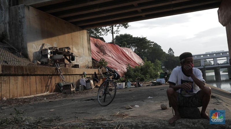 Warga bersantai di sekitar Banjir Kanal Timur di depan lokasi tanah longsor yang ditutupi terpal besar di pinggir Kanal Banjir Timur, Jakarta, Kamis (18/6/2020). Longsor yang terjadi pada awal Januari 2020 tersebut belum diperbaiki dan hanya ditutupi terpal besar guna mengantisipasi longsor susulan. Warga setempat mengaku khawatir terjadi longsor susulan karena terpal dan karung pasir yang digunakan untuk menutupi lokasi longsor kian rapuh. Pantauan CNBC Indonesia disekitar lokasi banyak aktivitas yang bermain dan berkumpul. Seperti diketahui longsor tersebut terjadi akibat hujan deras saat awal tahun lalu. Penutupan itu guna mencegah longsor susulan.  (CNBC Indonesia/ Muhammad Sabki)