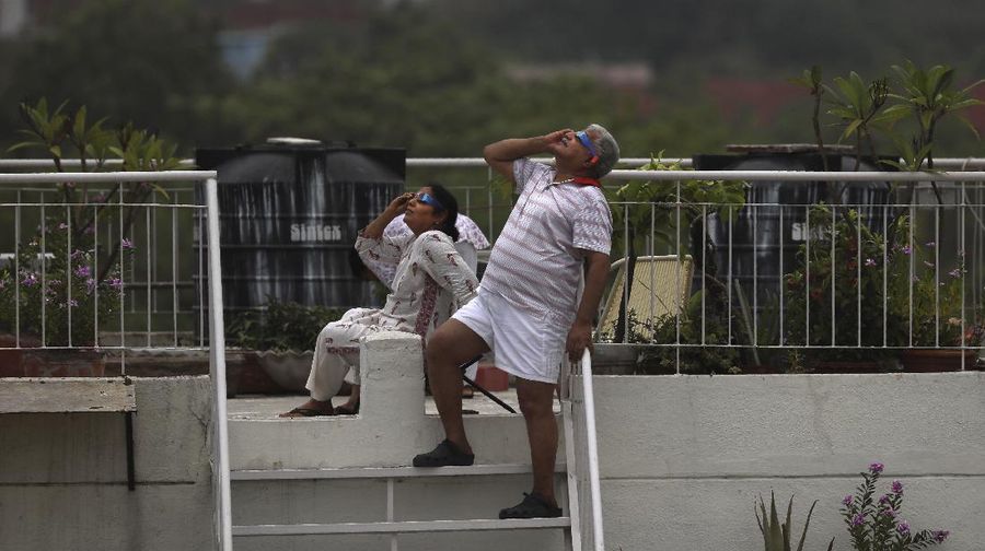 A man tries to take photos as a solar eclipse is seen over the sky in Chiayi City, southwest of Taiwan, Sunday, June 21, 2020. (AP Photo/Chiang Ying-ying)