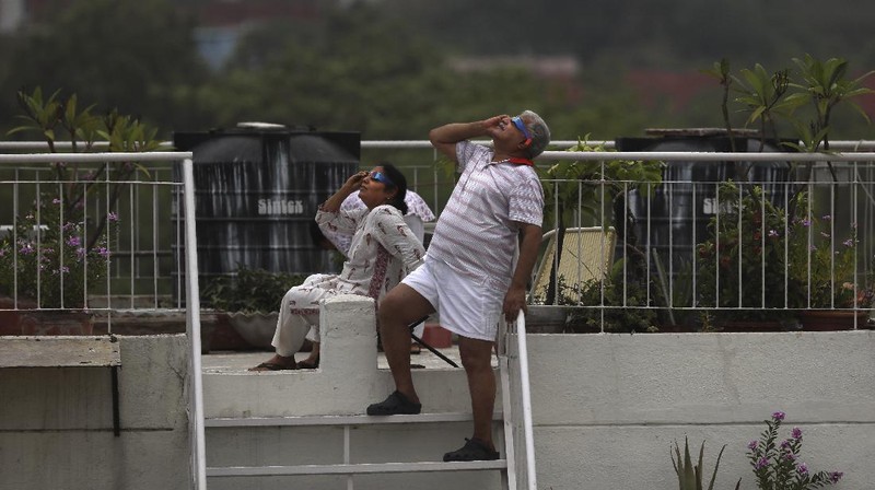 A man tries to take photos as a solar eclipse is seen over the sky in Chiayi City, southwest of Taiwan, Sunday, June 21, 2020. (AP Photo/Chiang Ying-ying)