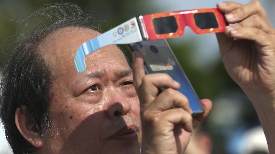 A man tries to take photos as a solar eclipse is seen over the sky in Chiayi City, southwest of Taiwan, Sunday, June 21, 2020. (AP Photo/Chiang Ying-ying)