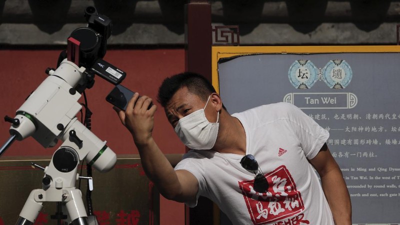 A man tries to take photos as a solar eclipse is seen over the sky in Chiayi City, southwest of Taiwan, Sunday, June 21, 2020. (AP Photo/Chiang Ying-ying)