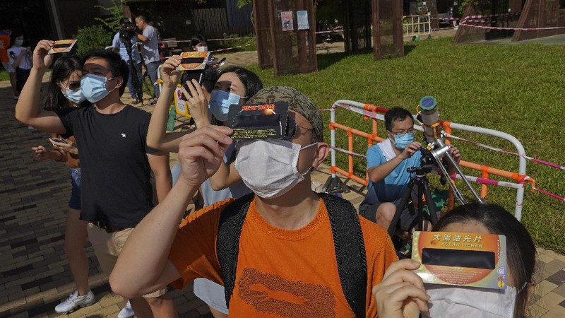 A man tries to take photos as a solar eclipse is seen over the sky in Chiayi City, southwest of Taiwan, Sunday, June 21, 2020. (AP Photo/Chiang Ying-ying)