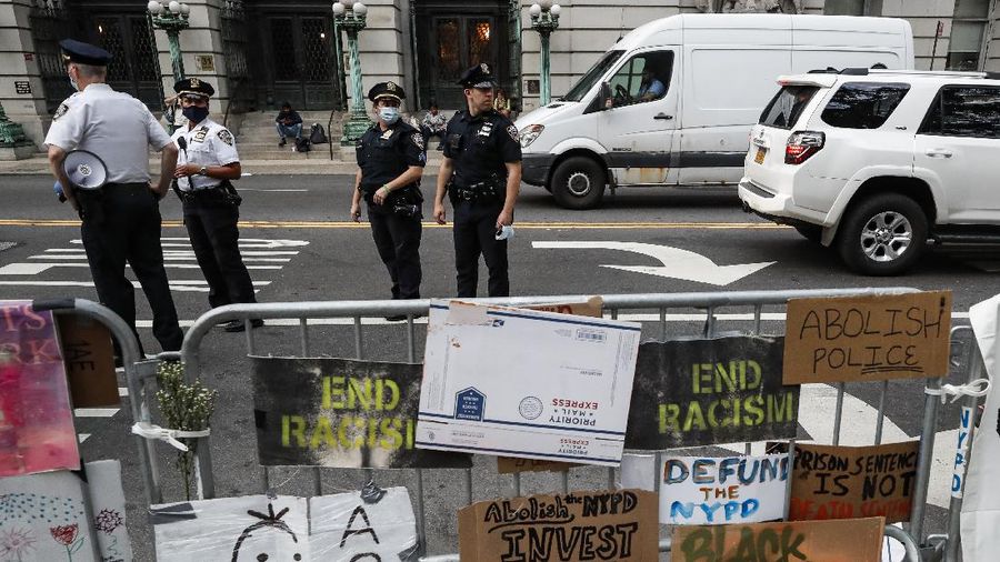 Protesters rest in a grassy area surrounded by signs calling for changes to police policies and practices at an encampment outside City Hall, Friday, June 26, 2020, in New York. (AP Photo/John Minchillo)