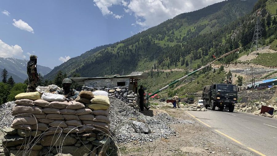 Indian paramilitary soldiers keep guard as Indian army convoy moves on the Srinagar- Ladakh highway at Gagangeer, north-east of Srinagar, India, Thursday, June 18, 2020. India on Thursday cautioned China against making 