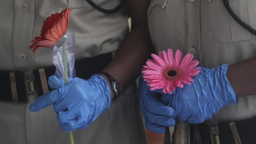 Security officers hold flowers given to them as a gesture of gratitude at the end of a free medical camp in Dharavi, one of Asia's biggest slums, in Mumbai, India, Friday, June 26, 2020. India is the fourth hardest-hit country by the pandemic in the world after the U.S., Russia and Brazil. (AP Photo/Rafiq Maqbool)