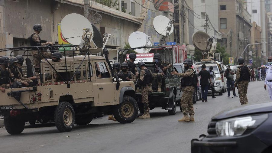 In this image made from a video, police and investigators gather around a car used by attackers, in Karachi, Pakistan Monday, June 29, 2020. Militants attacked the stock exchange in the Pakistani city of Karachi on Monday, according to police. (AP Photo)