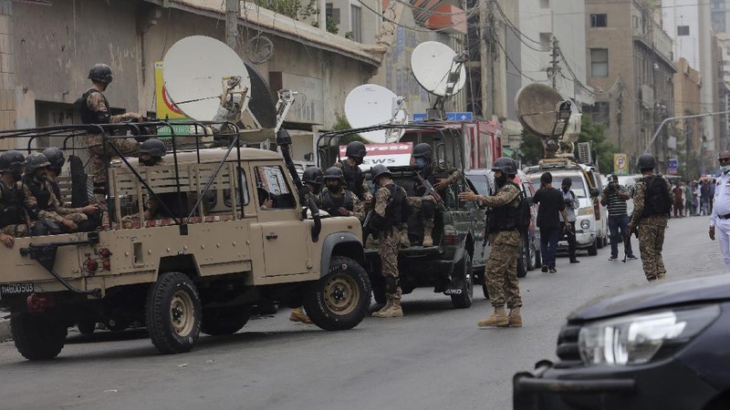 In this image made from a video, police and investigators gather around a car used by attackers, in Karachi, Pakistan Monday, June 29, 2020. Militants attacked the stock exchange in the Pakistani city of Karachi on Monday, according to police. (AP Photo)