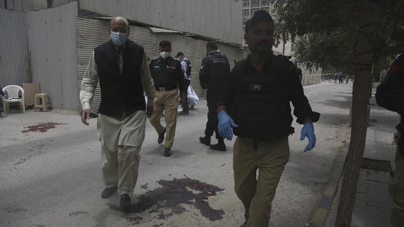 In this image made from a video, police and investigators gather around a car used by attackers, in Karachi, Pakistan Monday, June 29, 2020. Militants attacked the stock exchange in the Pakistani city of Karachi on Monday, according to police. (AP Photo)