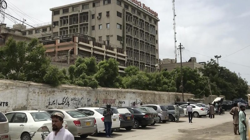 In this image made from a video, police and investigators gather around a car used by attackers, in Karachi, Pakistan Monday, June 29, 2020. Militants attacked the stock exchange in the Pakistani city of Karachi on Monday, according to police. (AP Photo)