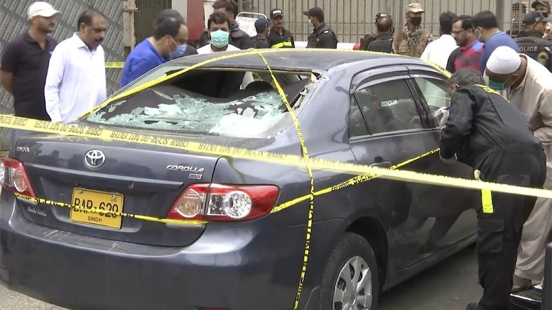 In this image made from a video, police and investigators gather around a car used by attackers, in Karachi, Pakistan Monday, June 29, 2020. Militants attacked the stock exchange in the Pakistani city of Karachi on Monday, according to police. (AP Photo)
