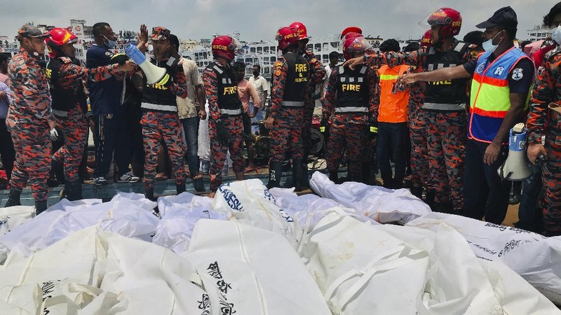 People watch as rescuers bring bodies of passengers recovered from Buriganga River in Dhaka, Bangladesh, Monday, June 29, 2020. A ferry carrying about 100 passengers capsized after being hit Monday by a larger vessel in a Bangladeshi river, killing at least 28 people, officials said. (AP Photo/Al-emrun Garjon)