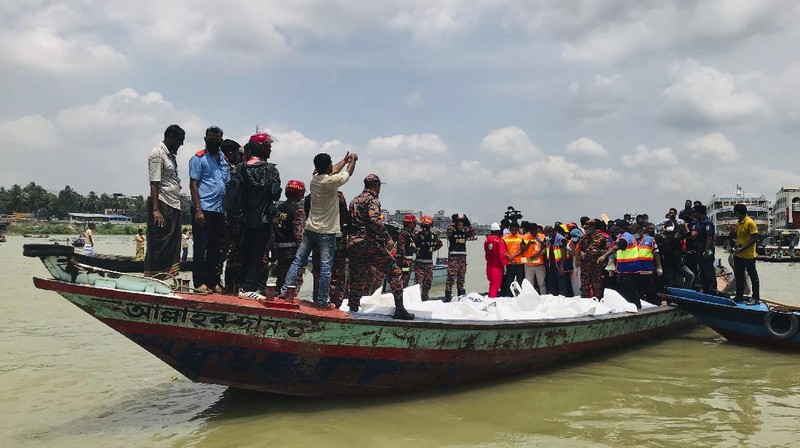 People watch as rescuers bring bodies of passengers recovered from Buriganga River in Dhaka, Bangladesh, Monday, June 29, 2020. A ferry carrying about 100 passengers capsized after being hit Monday by a larger vessel in a Bangladeshi river, killing at least 28 people, officials said. (AP Photo/Al-emrun Garjon)