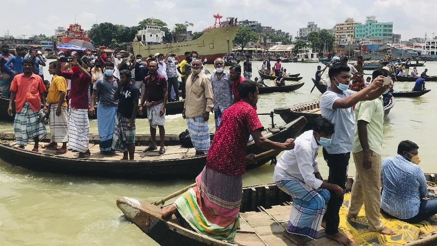 People watch as rescuers bring bodies of passengers recovered from Buriganga River in Dhaka, Bangladesh, Monday, June 29, 2020. A ferry carrying about 100 passengers capsized after being hit Monday by a larger vessel in a Bangladeshi river, killing at least 28 people, officials said. (AP Photo/Al-emrun Garjon)