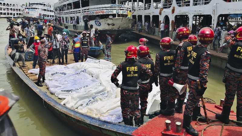 People watch as rescuers bring bodies of passengers recovered from Buriganga River in Dhaka, Bangladesh, Monday, June 29, 2020. A ferry carrying about 100 passengers capsized after being hit Monday by a larger vessel in a Bangladeshi river, killing at least 28 people, officials said. (AP Photo/Al-emrun Garjon)