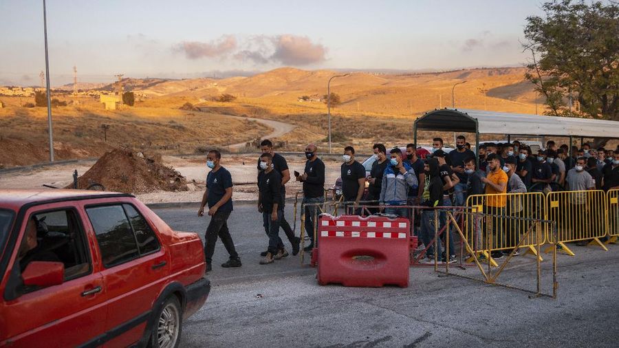 Palestinians laborers line up to cross a checkpoint at the entrance to the Israeli settlement of Maale Adumim, near Jerusalem, Tuesday, June 30, 2020. Israeli Prime Minister Benjamin Netanyahu appears determined to carry out his pledge to begin annexing parts of the occupied West Bank, possibly as soon as Wednesday. (AP Photo/Oded Balilty)