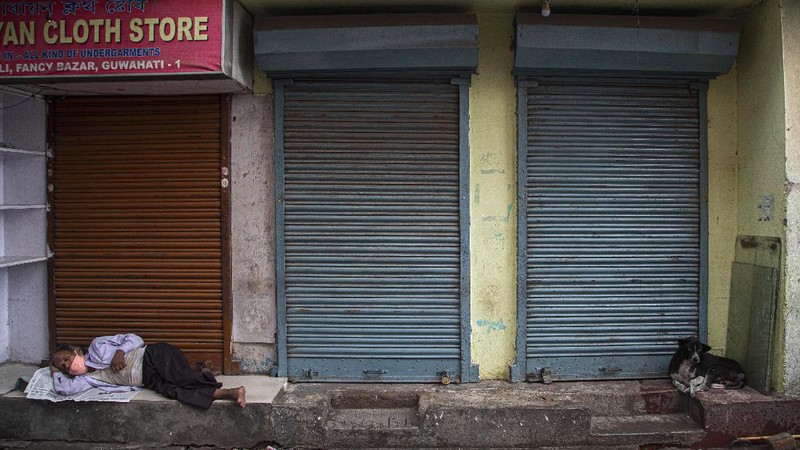 An Indian man wearing a face mask as a precaution against the coronavirus sleeps outside closed shops during the reimposed lockdown in Gauhati, India, Monday, June 29, 2020. India has reported a new daily record of nearly 20,000 new infections as several Indian states reimpose partial or full lockdowns to stem the spread of the coronavirus. (AP Photo/Anupam Nath)