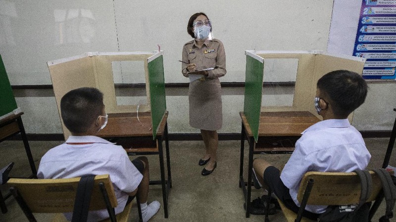 Teachers and students wearing protective gear to help curb the spread of the coronavirus as they pray before class at Samkhok School in Pathum Thani, outside Bangkok, Wednesday, July 1, 2020. Thailand has begun a fifth phase of relaxations of COVID-19 restrictions, allowing the reopening of schools and high-risk entertainment venues such as pubs and massage parlors that had been shut since mid-March. (AP Photo/Sakchai Lalit)