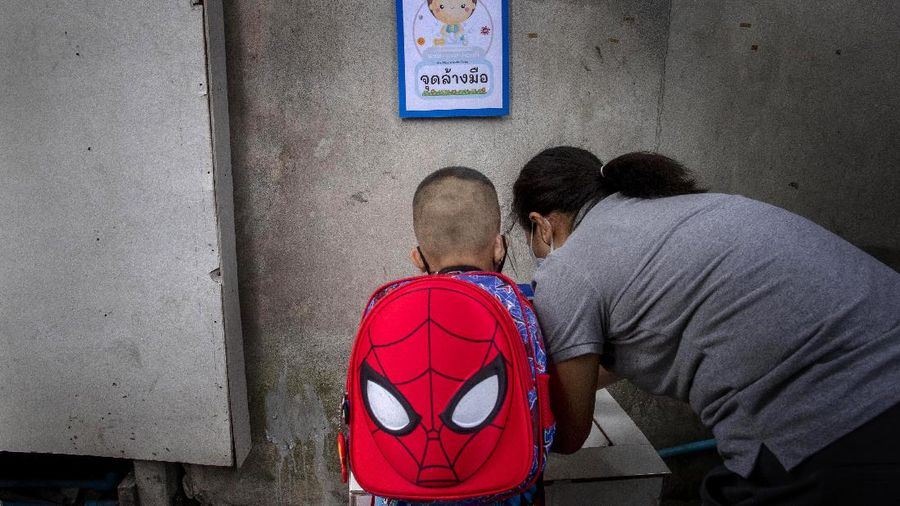 Teachers and students wearing protective gear to help curb the spread of the coronavirus as they pray before class at Samkhok School in Pathum Thani, outside Bangkok, Wednesday, July 1, 2020. Thailand has begun a fifth phase of relaxations of COVID-19 restrictions, allowing the reopening of schools and high-risk entertainment venues such as pubs and massage parlors that had been shut since mid-March. (AP Photo/Sakchai Lalit)