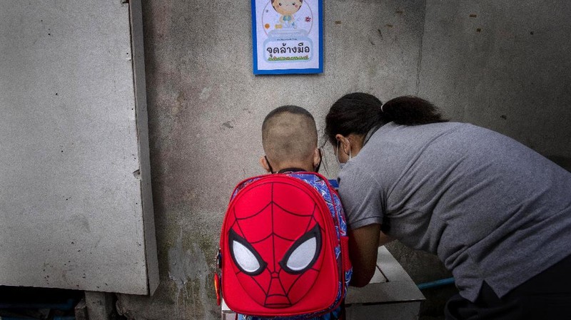 Teachers and students wearing protective gear to help curb the spread of the coronavirus as they pray before class at Samkhok School in Pathum Thani, outside Bangkok, Wednesday, July 1, 2020. Thailand has begun a fifth phase of relaxations of COVID-19 restrictions, allowing the reopening of schools and high-risk entertainment venues such as pubs and massage parlors that had been shut since mid-March. (AP Photo/Sakchai Lalit)