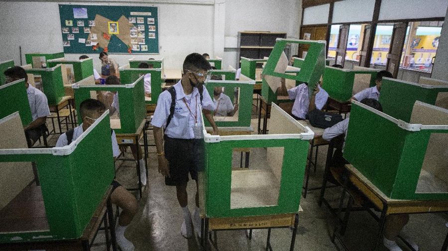 Teachers and students wearing protective gear to help curb the spread of the coronavirus as they pray before class at Samkhok School in Pathum Thani, outside Bangkok, Wednesday, July 1, 2020. Thailand has begun a fifth phase of relaxations of COVID-19 restrictions, allowing the reopening of schools and high-risk entertainment venues such as pubs and massage parlors that had been shut since mid-March. (AP Photo/Sakchai Lalit)