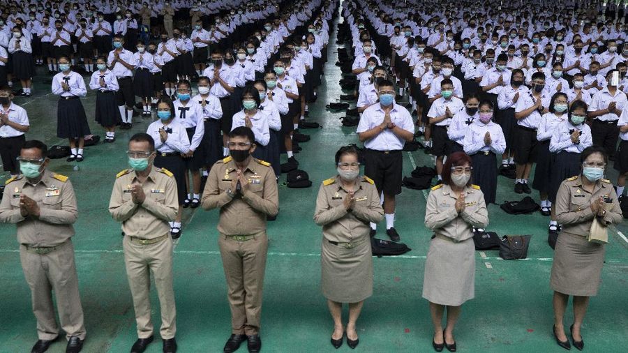 Teachers and students wearing protective gear to help curb the spread of the coronavirus as they pray before class at Samkhok School in Pathum Thani, outside Bangkok, Wednesday, July 1, 2020. Thailand has begun a fifth phase of relaxations of COVID-19 restrictions, allowing the reopening of schools and high-risk entertainment venues such as pubs and massage parlors that had been shut since mid-March. (AP Photo/Sakchai Lalit)