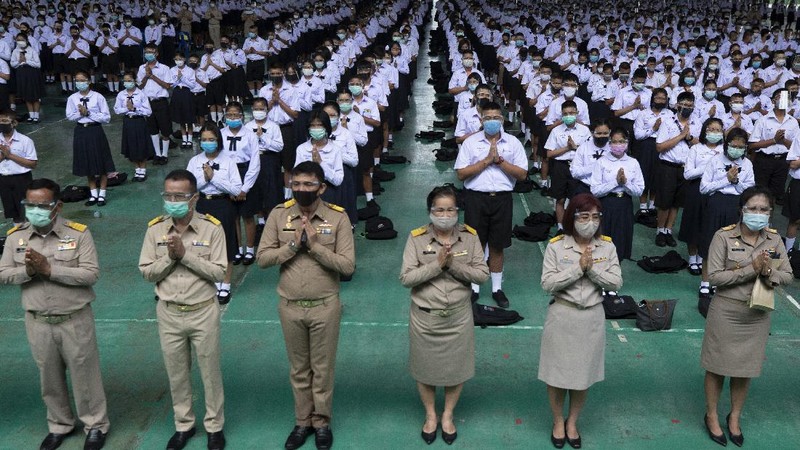 Teachers and students wearing protective gear to help curb the spread of the coronavirus as they pray before class at Samkhok School in Pathum Thani, outside Bangkok, Wednesday, July 1, 2020. Thailand has begun a fifth phase of relaxations of COVID-19 restrictions, allowing the reopening of schools and high-risk entertainment venues such as pubs and massage parlors that had been shut since mid-March. (AP Photo/Sakchai Lalit)