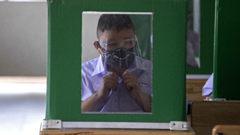 Teachers and students wearing protective gear to help curb the spread of the coronavirus as they pray before class at Samkhok School in Pathum Thani, outside Bangkok, Wednesday, July 1, 2020. Thailand has begun a fifth phase of relaxations of COVID-19 restrictions, allowing the reopening of schools and high-risk entertainment venues such as pubs and massage parlors that had been shut since mid-March. (AP Photo/Sakchai Lalit)