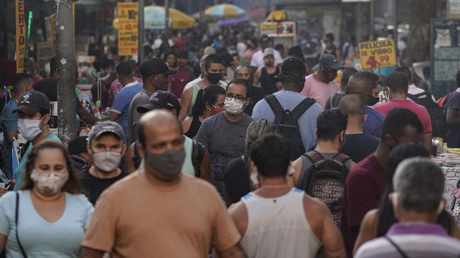 Pedestrians, some wearing protective face masks, walk through a street market in downtown Rio de Janeiro, Brazil, Thursday, June 25, 2020. With Latin America now the epicenter of the new coronavirus pandemic, but with hundreds of millions relying on these markets for food and livelihoods, the debate now centers on whether and how they can ever operate safely. (AP Photo/Leo Correa)
