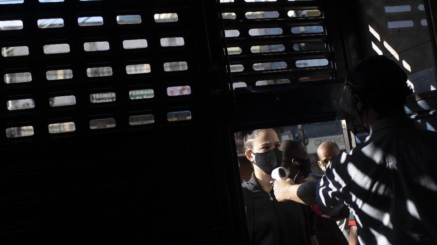 A vendor has her temperature checked before entering the Madureira Market amid the new coronavirus pandemic, in Rio de Janeiro, Brazil, Wednesday, June 17, 2020. As the pandemic swamps countries from Mexico to Argentina, public health officials are struggling to contain outbreaks seeded at Latin America’s iconic covered food markets, a beloved, essential feature of life in the region and a near-perfect setting for spreading the disease. (AP Photo/Silvia Izquierdo)