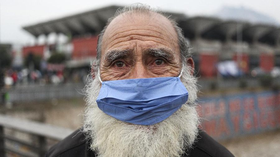 A man wearing a protective face mask as a precaution amid the new coronavirus pandemic, poses for a photo after buying groceries at a market in Santiago, Chile, Monday, June 8, 2020.  With Latin America now the epicenter of the pandemic, but with hundreds of millions relying on these markets for food and livelihoods, the debate now centers on whether and how they can operate safely. (AP Photo/Esteban Felix)