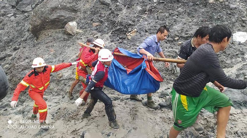 In this photo released from Myanmar Fire Service Department, rescuers carry a recovered body of a victim in a landslide from a jade mining area in Hpakant, Kachin state, northern Myanmar Thursday, July 2, 2020. Myanmar government says a landslide at a jade mine has killed dozens of people. (Myanmar Fire Service Department via AP)