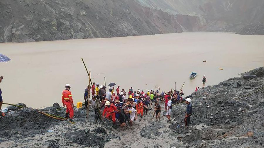 In this photo released from Myanmar Fire Service Department, rescuers carry a recovered body of a victim in a landslide from a jade mining area in Hpakant, Kachin state, northern Myanmar Thursday, July 2, 2020. Myanmar government says a landslide at a jade mine has killed dozens of people. (Myanmar Fire Service Department via AP)