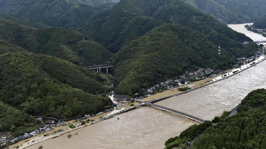 A bridge over the Kuma River is washed away by a flood in Yatsushiro, Kumamoto prefecture, southwestern Japan, Saturday, July 4, 2020. Heavy rain triggered flooding and mudslides on Saturday, leaving more than a dozen missing and others stranded on rooftops waiting to be rescued. More than 75,000 residents in the prefectures of Kumamoto and Kagoshima were asked to evacuate following pounding rains overnight. (Kyodo News via AP)