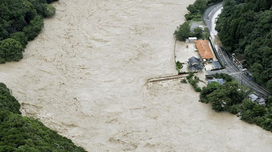 A bridge over the Kuma River is washed away by a flood in Yatsushiro, Kumamoto prefecture, southwestern Japan, Saturday, July 4, 2020. Heavy rain triggered flooding and mudslides on Saturday, leaving more than a dozen missing and others stranded on rooftops waiting to be rescued. More than 75,000 residents in the prefectures of Kumamoto and Kagoshima were asked to evacuate following pounding rains overnight. (Kyodo News via AP)