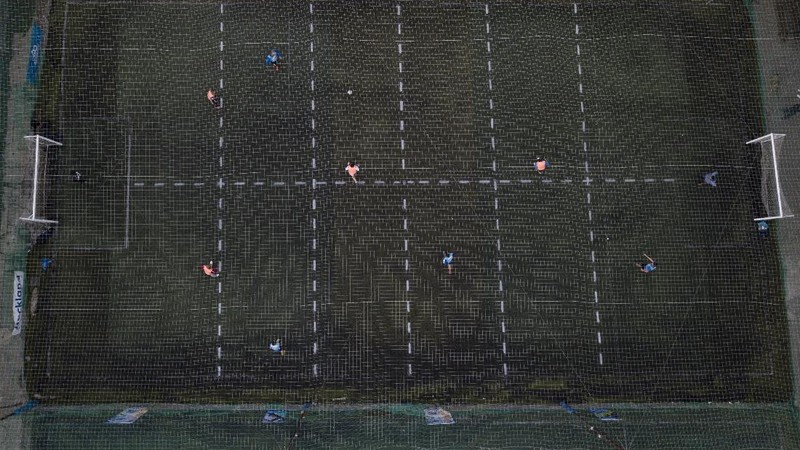 Martin Rodriguez controls the ball during an amateur soccer match at the Play Futbol 5 local club in Pergamino, Argentina, Wednesday, July 1, 2020. In order to continue playing amid government restrictions to curb the spread of the new coronavirus, the club divided its soccer field into 12 rectangles to mark limited areas for each player, keeping them from making physical contact. (AP Photo/Natacha Pisarenko)