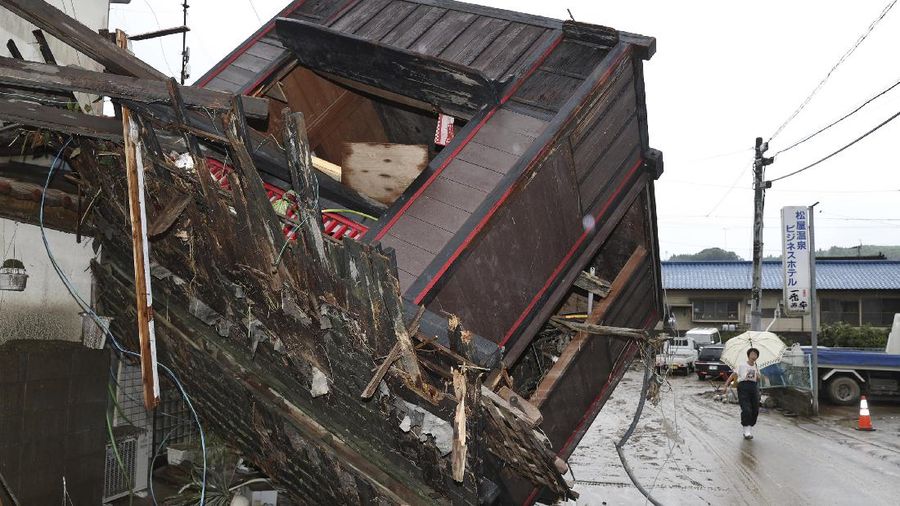 People carry a refrigerator out of a flooded office in Hitoyoshi city, Kumamoto prefecture, southwestern Japan, Tuesday, July 7, 2020. Floodwaters flowed down streets in southwestern Japanese towns hit by deadly rains that were expanding across the region Tuesday. (Yuki Sato/Kyodo News via AP)