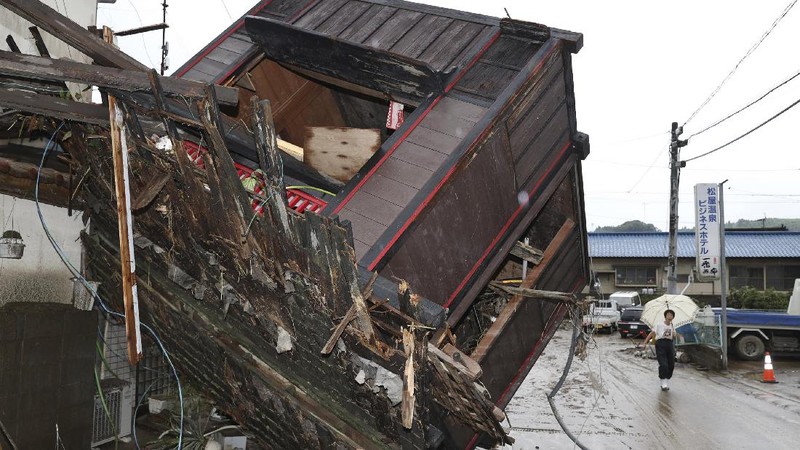 People carry a refrigerator out of a flooded office in Hitoyoshi city, Kumamoto prefecture, southwestern Japan, Tuesday, July 7, 2020. Floodwaters flowed down streets in southwestern Japanese towns hit by deadly rains that were expanding across the region Tuesday. (Yuki Sato/Kyodo News via AP)