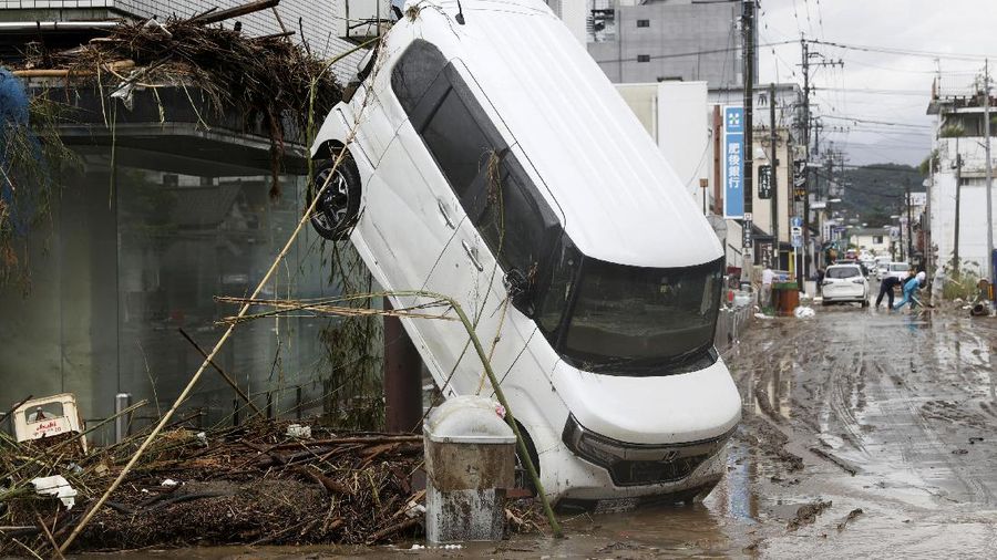 People carry a refrigerator out of a flooded office in Hitoyoshi city, Kumamoto prefecture, southwestern Japan, Tuesday, July 7, 2020. Floodwaters flowed down streets in southwestern Japanese towns hit by deadly rains that were expanding across the region Tuesday. (Yuki Sato/Kyodo News via AP)