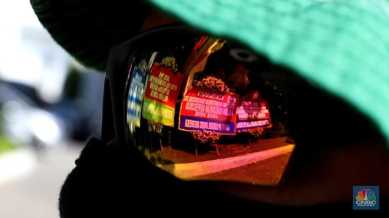 Warga melintas di depan karangan bunga sebagai protes terhadap PPDB DKI, berjejer di Balai Kota DKI Jakarta, Senin (6/7).Karangan bunga berisi pesan kekecewaan dari para orang tua murid berjejer di depan pintu masuk Balai Kota DKI Jakarta. Mereka kecewa dengan aturan penerimaan peserta didik baru (PPDB) DKI Jakarta. (CNBC Indonesia/ Muhammad Sabki)