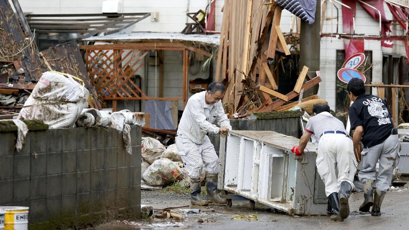 People carry a refrigerator out of a flooded office in Hitoyoshi city, Kumamoto prefecture, southwestern Japan, Tuesday, July 7, 2020. Floodwaters flowed down streets in southwestern Japanese towns hit by deadly rains that were expanding across the region Tuesday. (Yuki Sato/Kyodo News via AP)