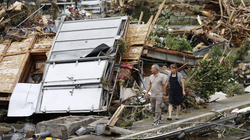 People carry a refrigerator out of a flooded office in Hitoyoshi city, Kumamoto prefecture, southwestern Japan, Tuesday, July 7, 2020. Floodwaters flowed down streets in southwestern Japanese towns hit by deadly rains that were expanding across the region Tuesday. (Yuki Sato/Kyodo News via AP)